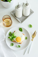 Croque madam sandwich with cheese and egg on white wooden table.