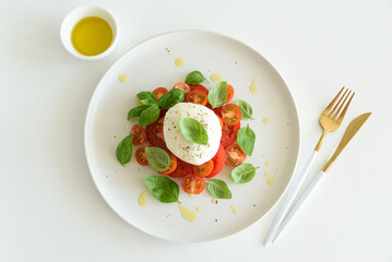 Salad Caprese with tomato, cherry, mozzarella and basil leaves on white wooden table