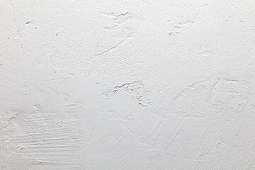 A white wall with a rough texture and a few lines