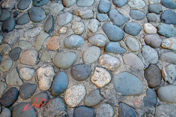 Round stones in the ground. Texture of the cobblestones in Park. Paved road for pedestrians. The paving stones.