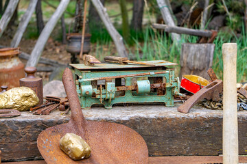 arrangement of old gold prospecting tools, including a rusty shovel with a fake gold nugget, a...