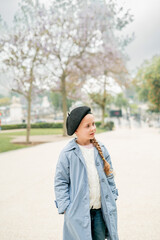 Fototapeta premium Little cute girl in beret enjoying walk in France with the Eiffel Tower in the background. Paris in spring.