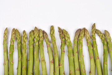 A row of fresh green asparagus spears is positioned along the bottom edge of a plain white...