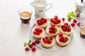 Classic New York cheesecakes in individual cups topped with fresh raspberry