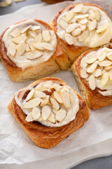 Cinnamon rolls topped with cream cheese frosting and sliced almonds