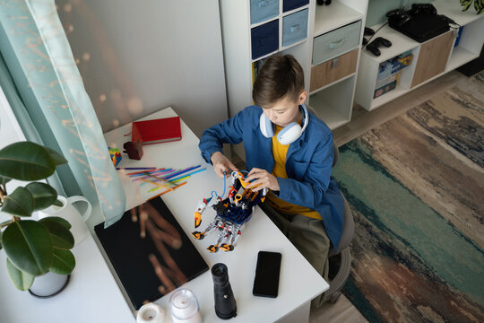 Young Boy Engaged in Building a Robot at Home Desk