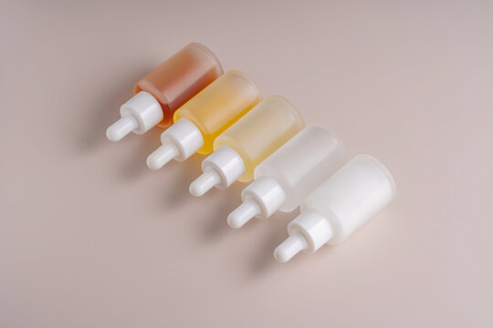 Row of gradient colored dropper bottles on beige background