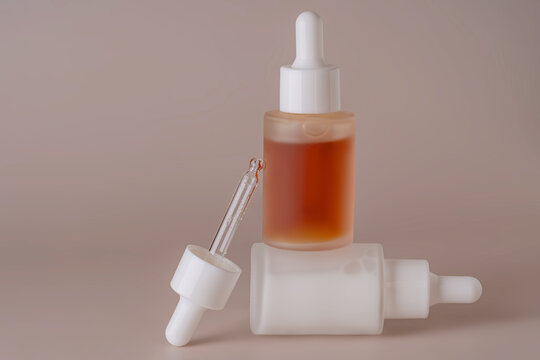 Set of dropper bottles with orange liquid on beige background