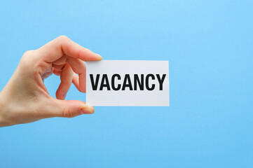 A hand holding a white card with the word Vacancy written on it