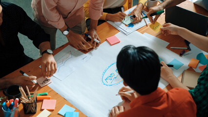 Top view of business team in casual cloth hand writing idea on sticky notes. Closeup of diverse people brainstorming marketing idea while sticking colorful sticky notes on mind mapping. Convocation.