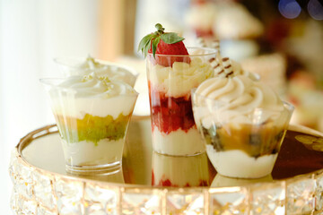 Close-up of several small glasses filled with delicious layered desserts. Gourmet Dessert Shooters on a Decorative Gold Stand.