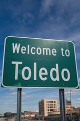 Obraz premium Welcome to Toledo Ohio Road Sign - City Entrance, Travel Destination, Midwestern Charm and Urban Landscape Under a Blue Sky
