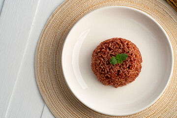 Cooked Thai Organic Red Jasmine Rice in white plate.semi-milled rice.including fiber, B vitamins and magnesium, offering a richer nutritional profile than traditional white rice.Top view.
