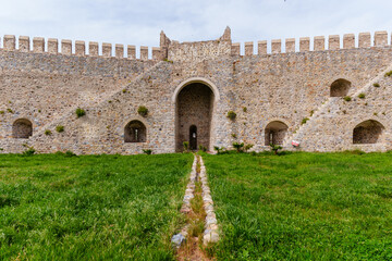 Historic Stone Fortress Wall With Arched Gate and Green Grass Landscape..
