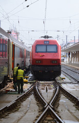 Obraz premium Trains stopped for maintenance, two employees washing the locomotive, holding a hose to pour water, rainy days