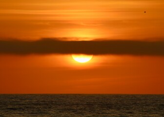 Beautiful dark orange sunset with long stripe cloud blocking part of the view in Pacific Beach, San diego