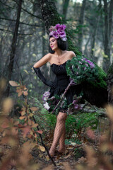 Slender beautiful brunette in the image of a forest fairy in full growth. Decorative cabbage instead of a bouquet. Artistic creative photography.