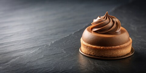 A single chocolate mousse tart with a swirl of cream on top, sitting on a black slate surface.