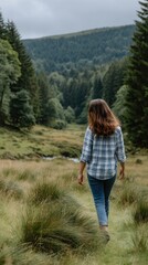 Naklejka premium Woman Walks Through Grassy Field Towards Forest Hills in Nature Scene