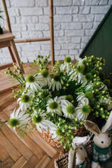 Beautiful white flowers arranged in a woven basket on a wooden floor in a stylish room