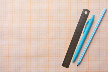 Concept of studying at school and back to school. Pens, pencils and ruler on school squared paper background, copy space
