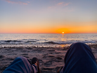 Serene evening scene showcasing a captivating sunset over the ocean while sitting on the beach. emphasizing relaxation and natural beauty.