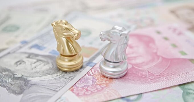 Trade war, reciprocal tariffs and global economic competition : Chess knight pieces on top of U.S. dollar and Chinese yuan notes, symbolizing the strategic economic rivalry between the US and China.