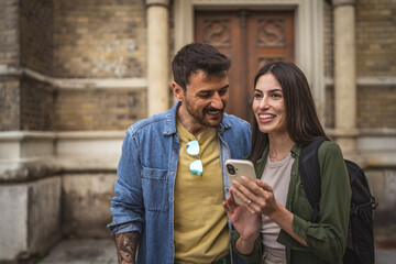 happy tourist couple use their mobile phone to navigate the city