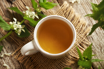 Fresh white dead-nettle flowers and leaves with a cup of herbal tea