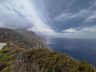 Stormy skies over the wild cliffs of Amorgos – dramatic coastal view with rugged terrain and...