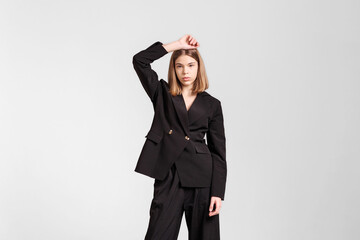 Fashion model poses confidently in modern black suit showcasing chic style and elegance in a minimalistic studio setting