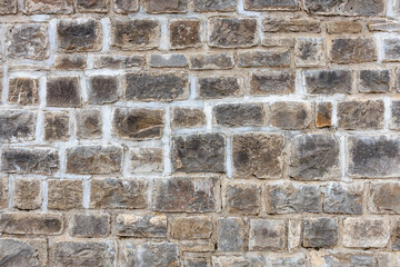 Textured stone wall with rectangular brown and gray brick pattern