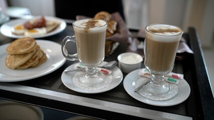Delicious breakfast with cappuccino, pancakes, and bacon served on a tray