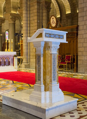 Principality of Monaco, France - July 9, 2024: Cathedral of Our Immaculate Lady. Decorated stone Pulpit in front of main altar. Red carpet