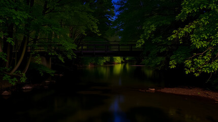 Calm Lynx Creek river flowing under the Foot Bridge alongside the green trees at night