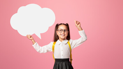 Modern school girl life. Smiling girl in school uniform and glasses points up to empty space and holds abstract word cloud, isolated on pink background