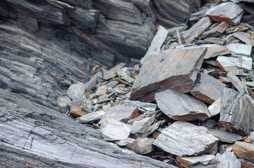 Close-up view of jagged slate rocks forming rough, textured layers in a mountain quarry. Perfect for backgrounds or geology concepts, highlighting natural rock structure.