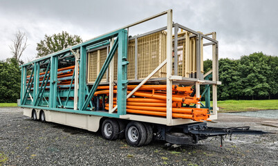 Flatbed trailer carrying metal pipes for a rollercoaster to a Fairground
