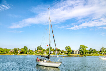 Sailboat moored in calm water with residential houses in background