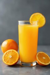 Glass of fresh orange juice, whole & halved oranges on gray background, fresh, fruit