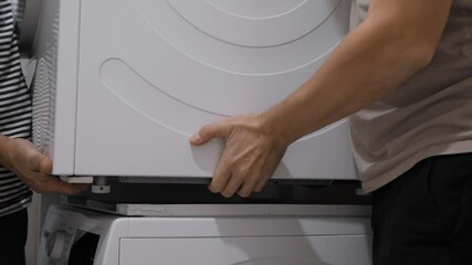 Teamwork together to dismantle a stacked washer and dryer. Two people work together to achieve great results and improve the efficiency of installing major appliances