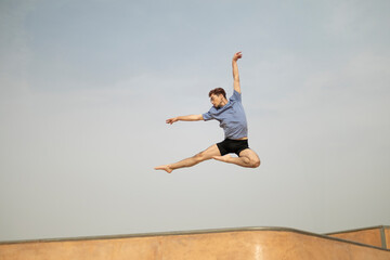 Ballet dancer performing a jump outdoors in a skate park