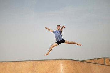 Young male dancer performing a jump in a skate park