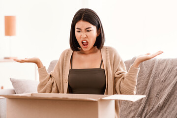Bad Delivery Service Concept. Angry mad asian woman screaming and spreading hands after unpacking...