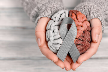 Woman holding brain models and brain cancer awareness ribbon