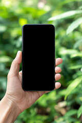 Hand holding smartphone in nature background  