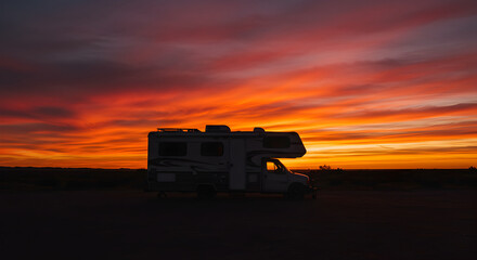 Fototapeta premium Recreational Vehicle Silhouette Against An Energetic Sunset Sky During Travel