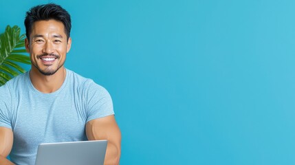 Smiling Hispanic man with a laptop against a bright blue background, radiating confidence and positivity.