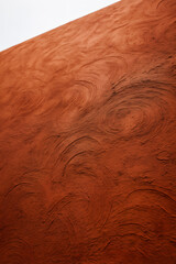 Fototapeta premium A close-up texture of a reddish-brown surface with swirling patterns, resembling a decorative wall finish or plaster
