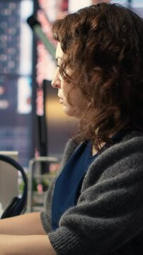 Vertical Video Young woman programming software code on her computer, using coding language for debugging tasks. Workspace with dual monitors helps with software engineering and web development